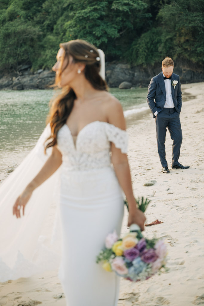 Romantic sunset beach wedding portraits of bride and groom embracing on a tropical shoreline in Thailand.